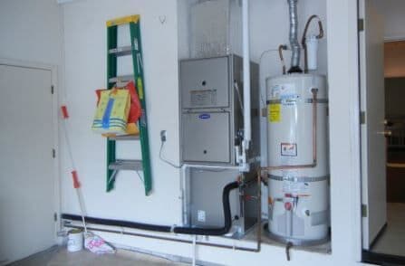 Interior laundry space featuring a green ladder, water heater, and furnace installation.