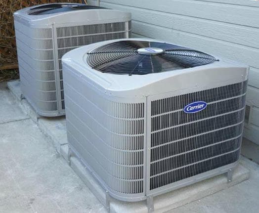 Carrier air conditioning units installed outside a home on a concrete base.
